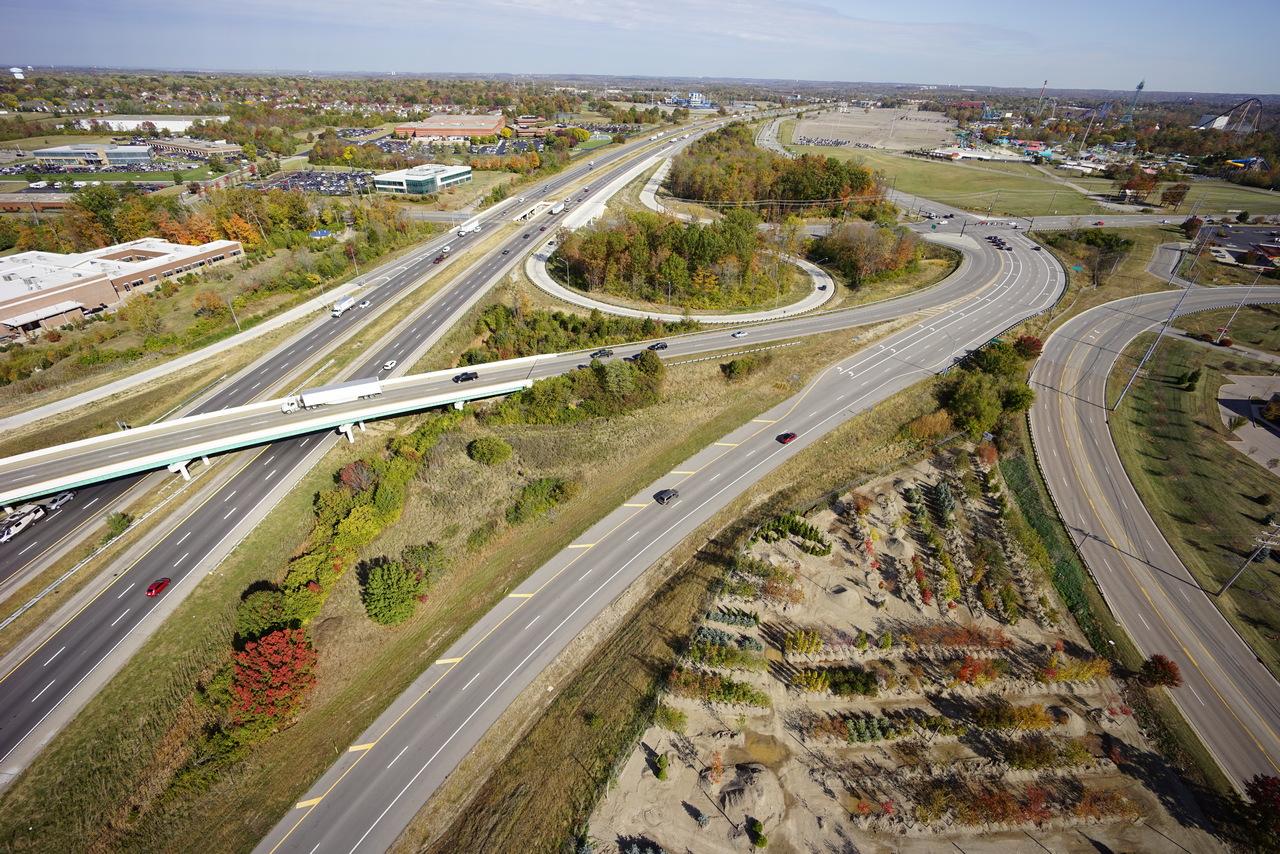 Aerial view of highway interchange with greenery and cars.