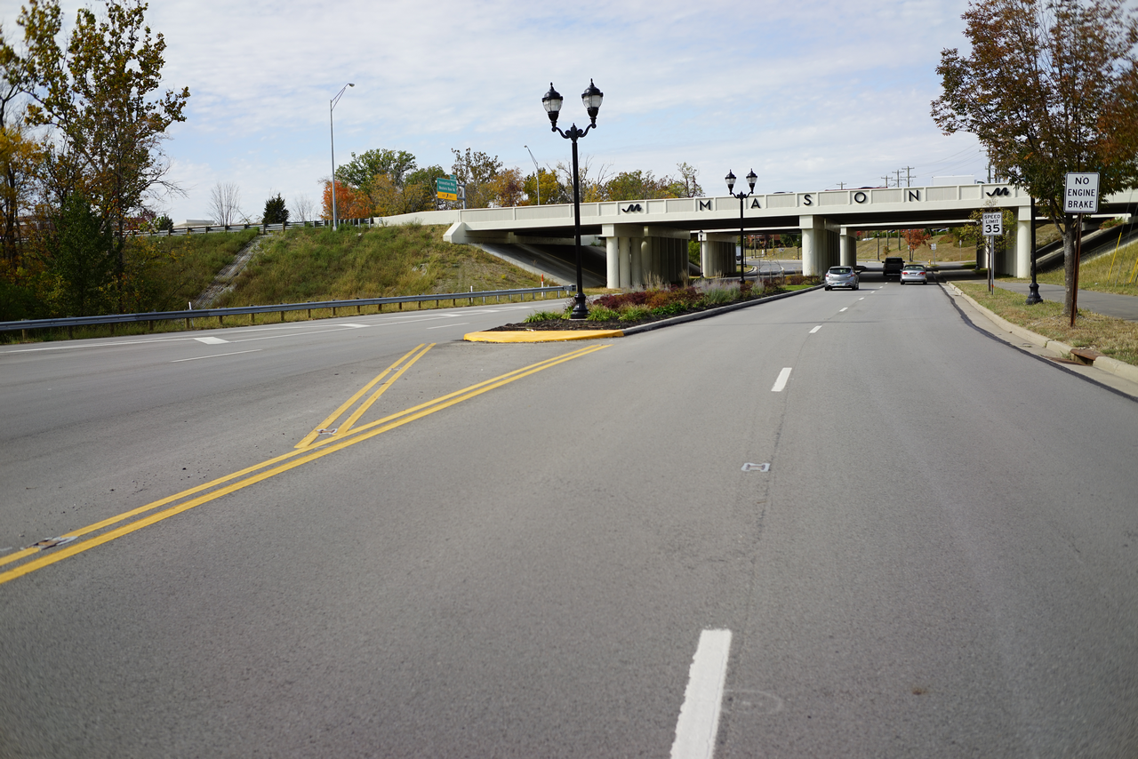 Road leading to an overpass on a clear day with autumn trees.