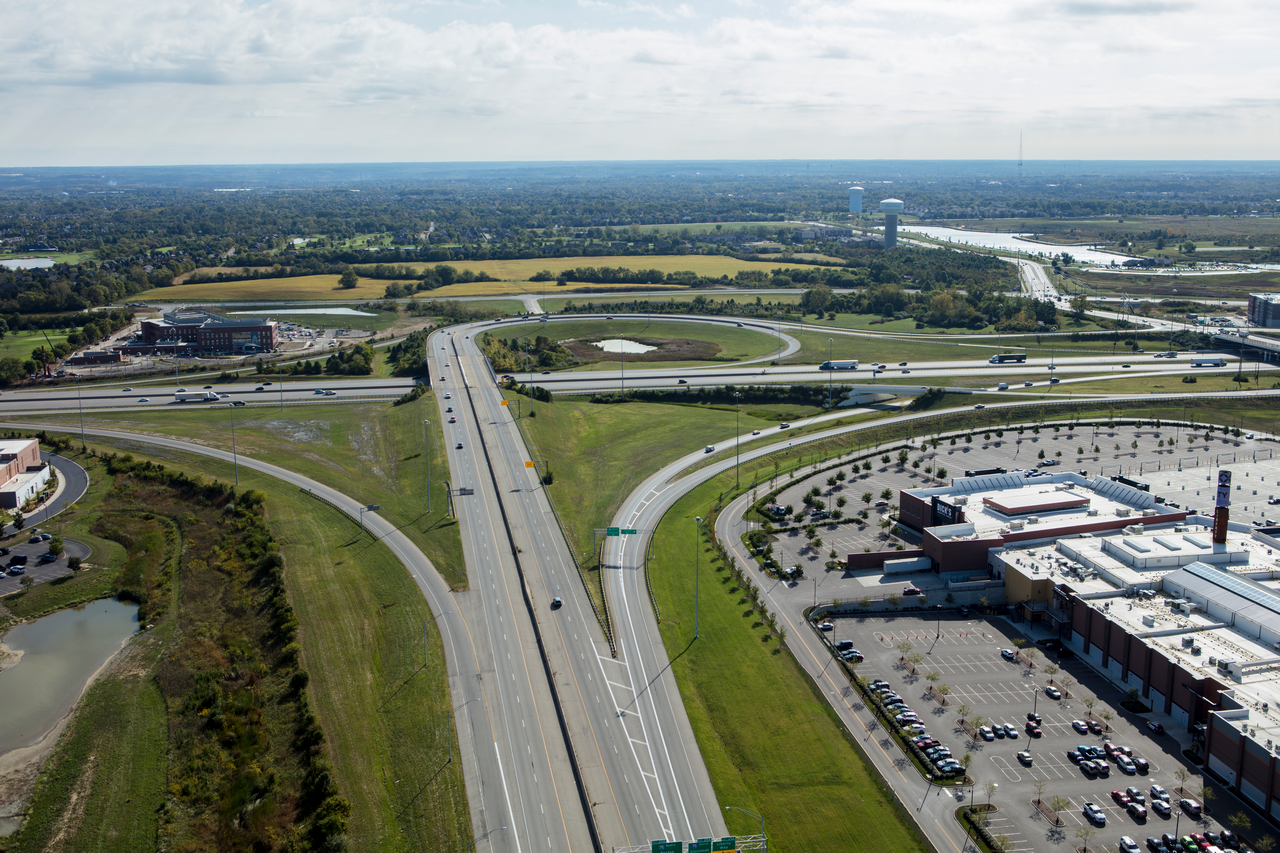 Aerial view of a highway intersection near a shopping center and fields.