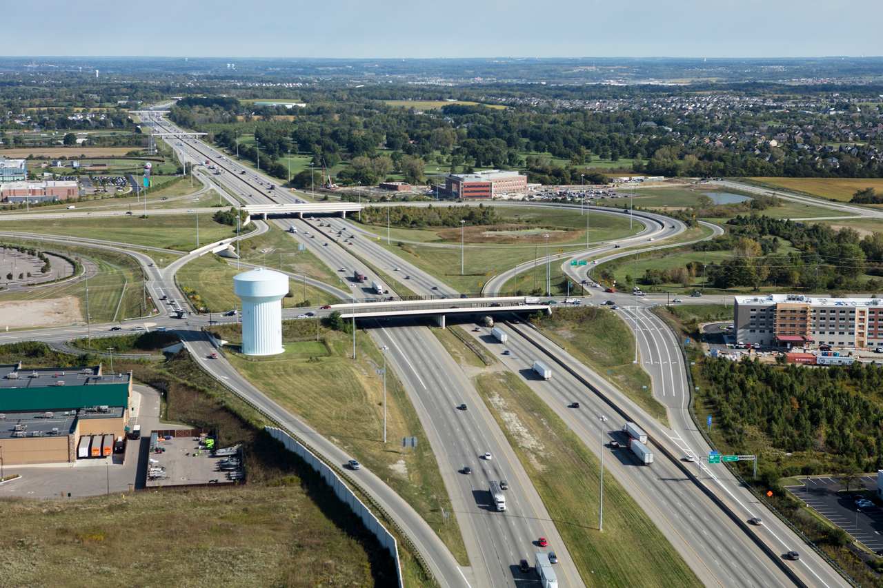 Aerial view of a busy highway interchange with traffic and surrounding greenery.
