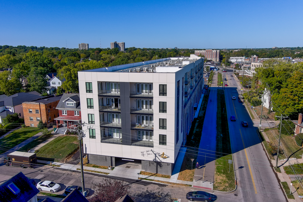 Modern apartment building on a sunny street corner, aerial view.