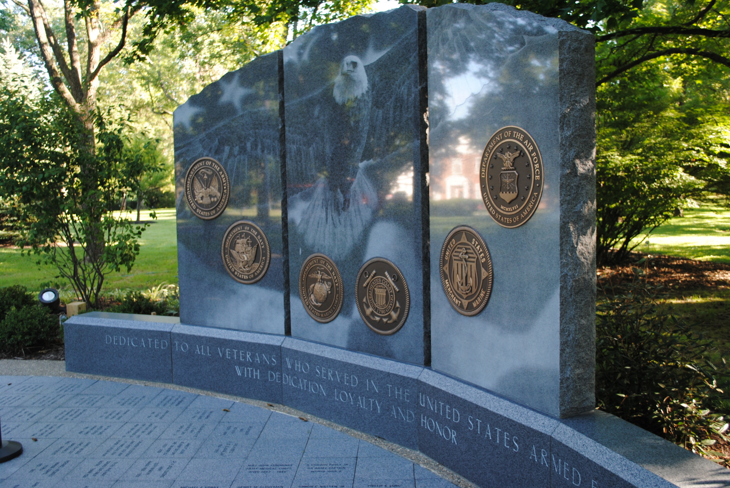 War memorial with military seals in a park setting.