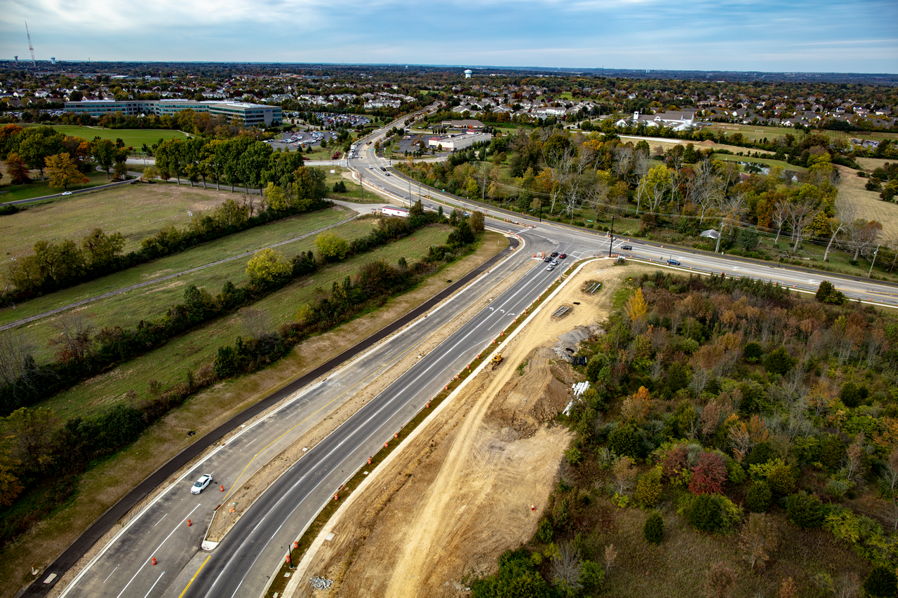 Aerial view of a highway under construction with surrounding fields and trees.