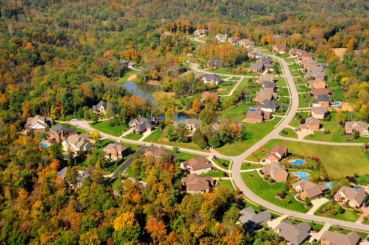 Aerial view of a suburban neighborhood with fall foliage and winding roads.