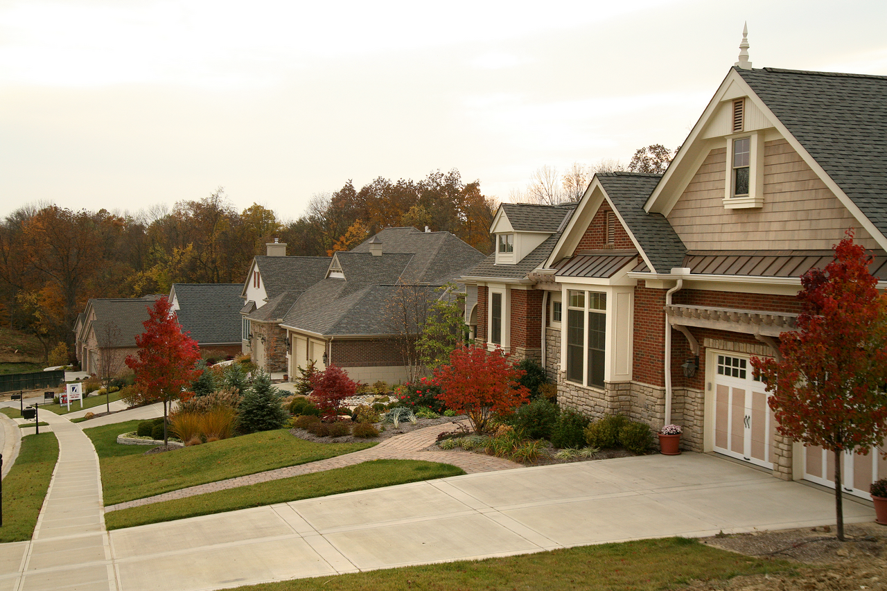 Suburban neighborhood with autumn trees and single-story houses at sunset.