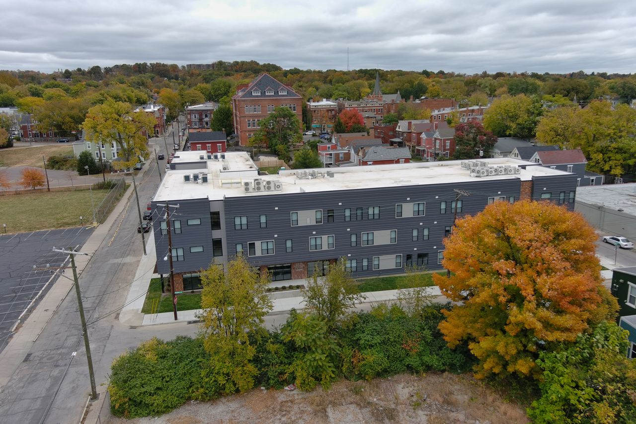 Aerial view of a gray building in a leafy neighborhood with fall foliage.