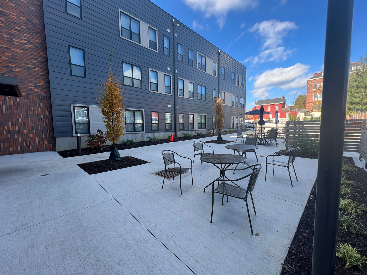 Outdoor patio with tables and chairs beside a modern building under a clear blue sky.