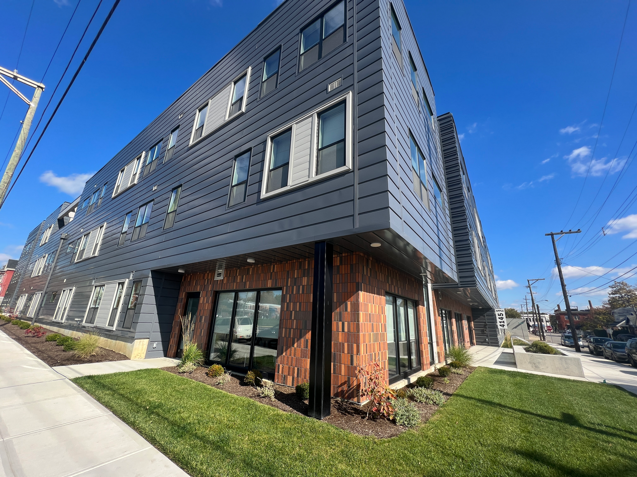 Modern building with blue paneling and large windows, under a clear blue sky.