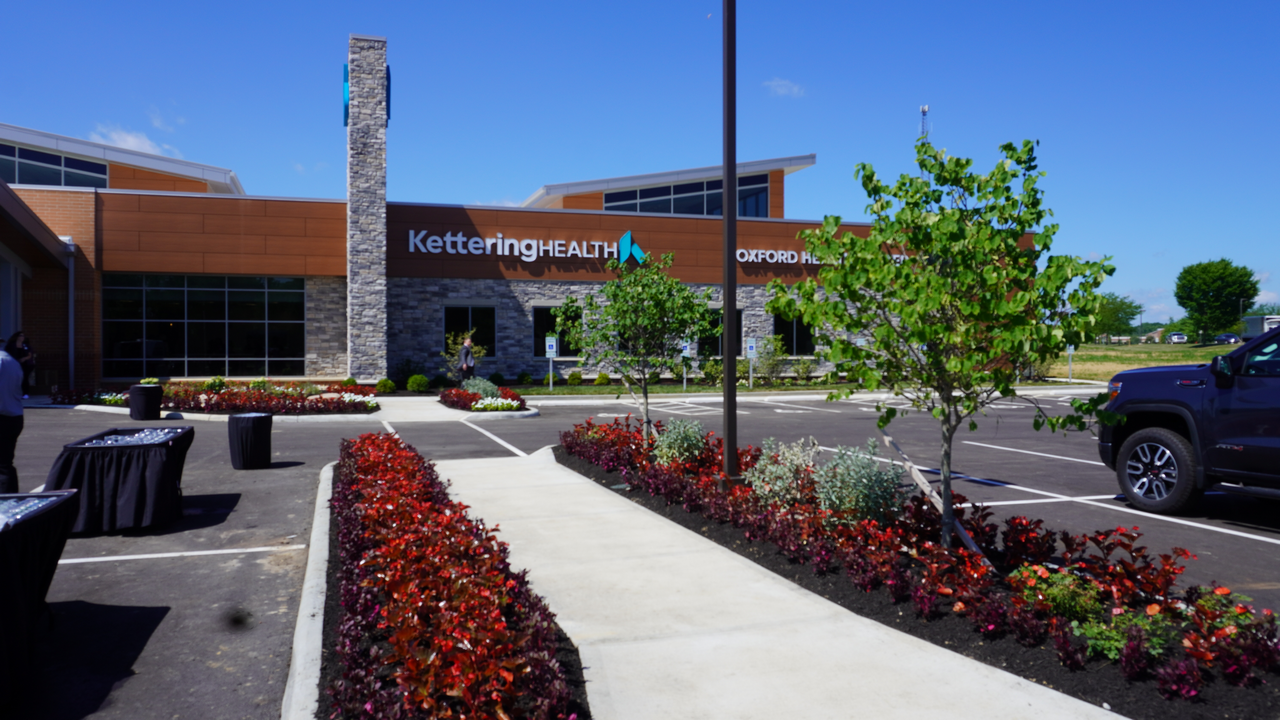 Modern building with stone accents, landscaped shrubs, and clear blue sky.
