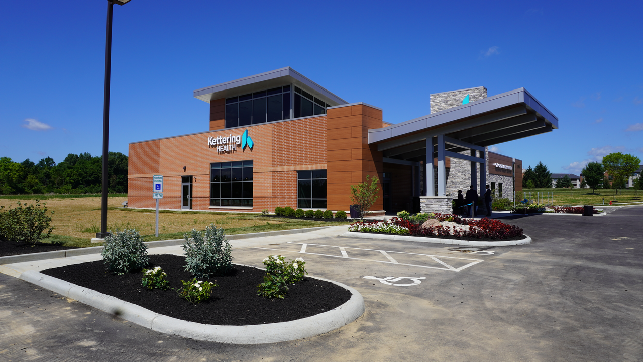 Modern brick building with a parking lot under a clear blue sky.