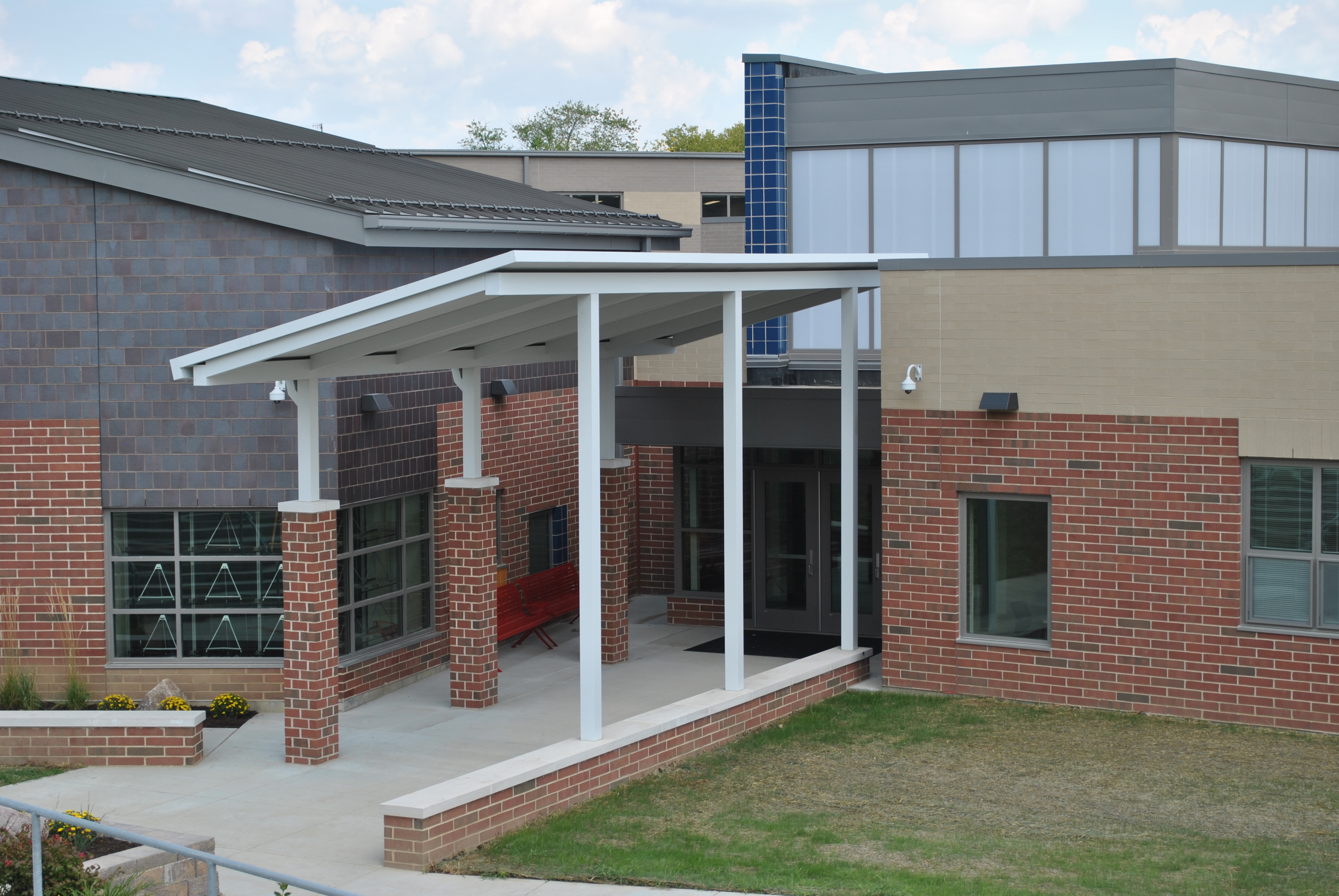 Entrance of a modern brick school building with large windows and a covered walkway.
