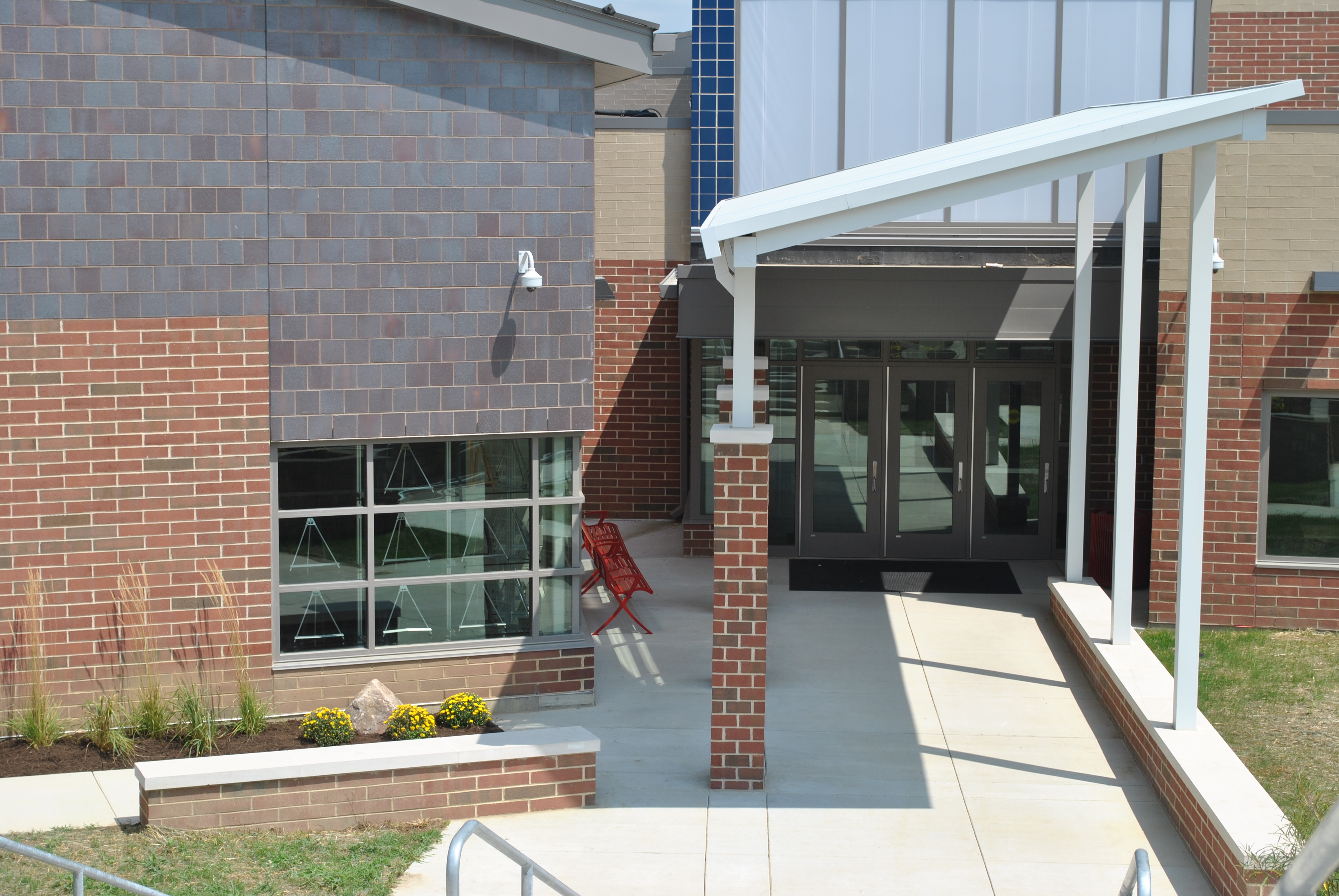 Entrance of a brick building with glass doors and large windows.