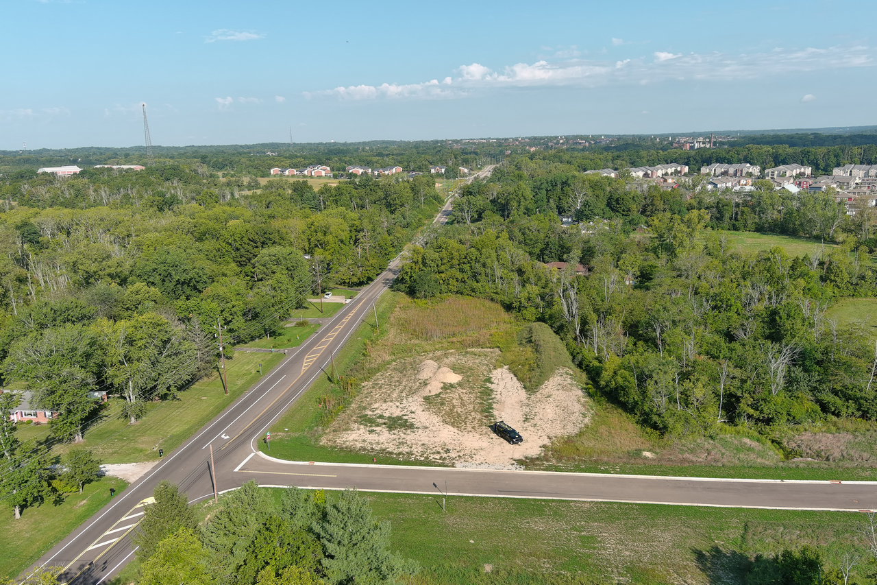 Aerial view of a rural road and green landscape under a blue sky.