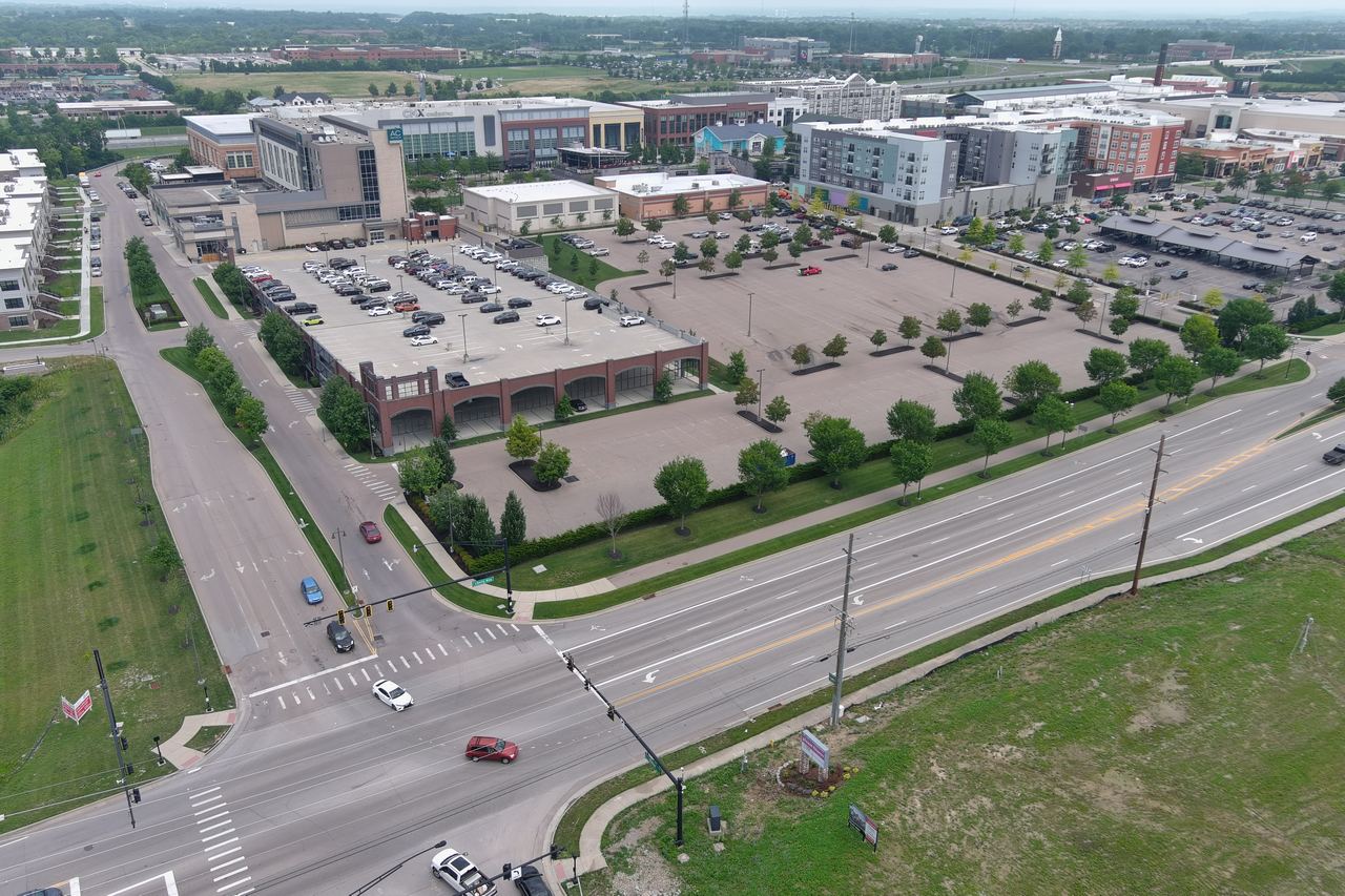 Aerial view of a shopping complex with parking lots and surrounding roads.