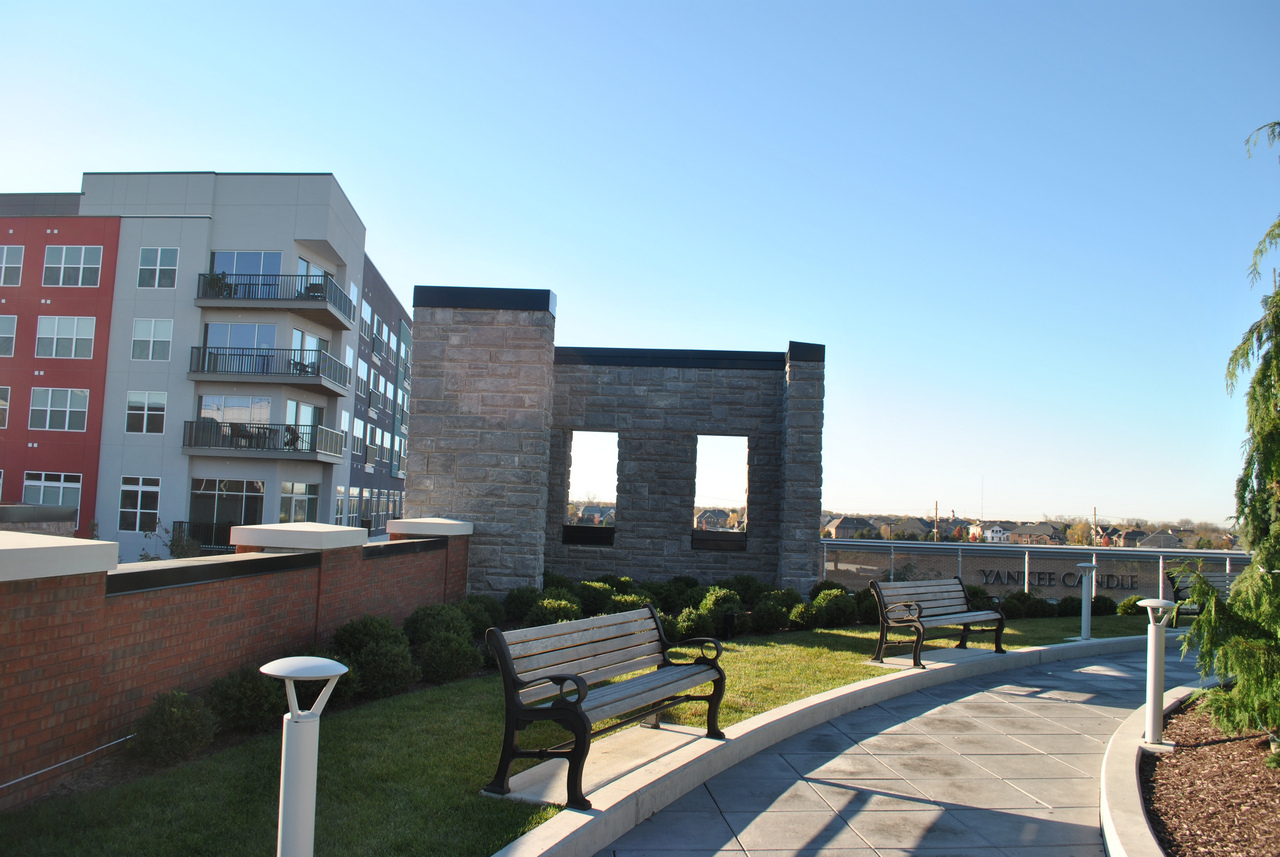Benches and pathway beside modern apartment buildings under a clear blue sky.