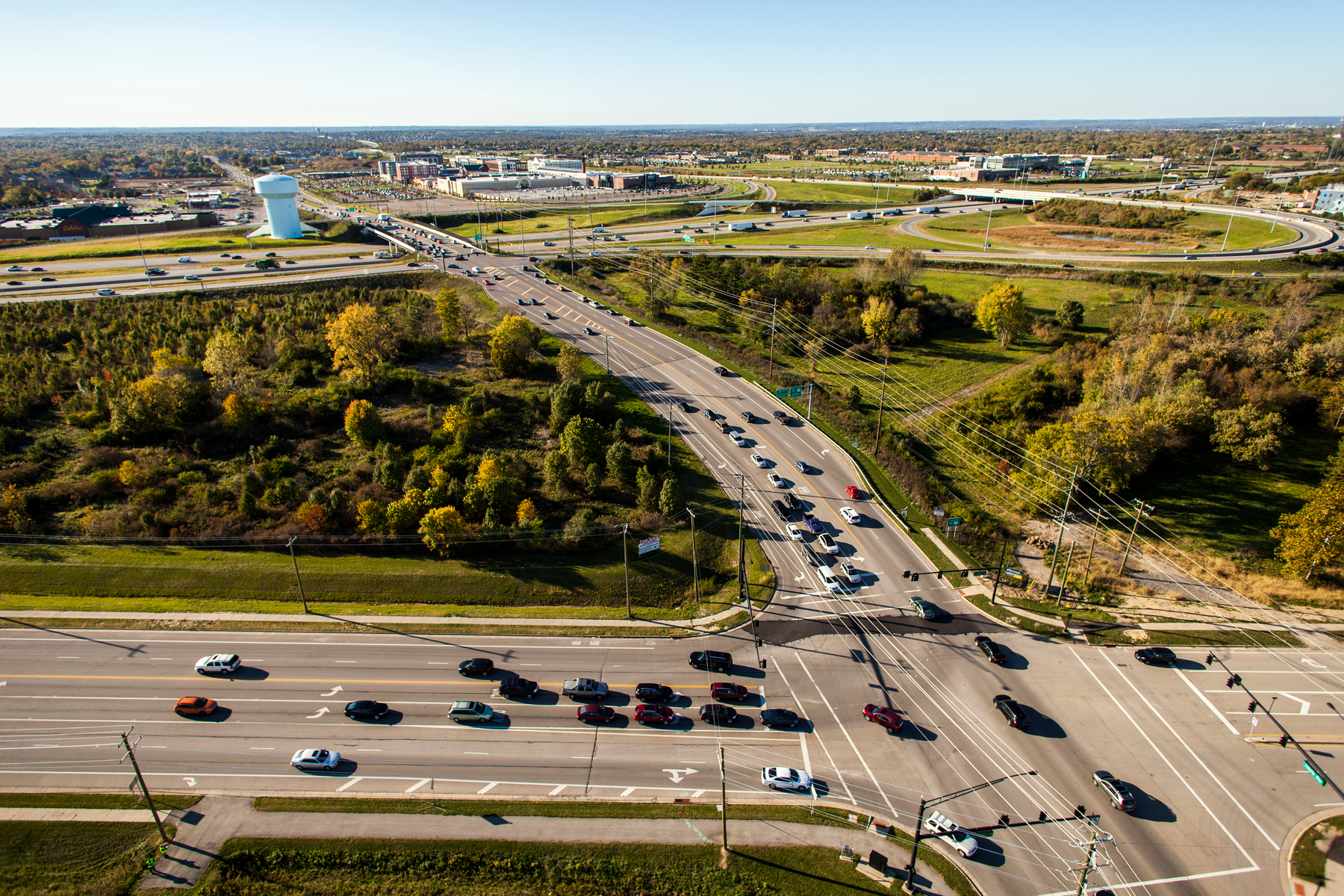 Aerial view of a busy intersection with trees and fields nearby.