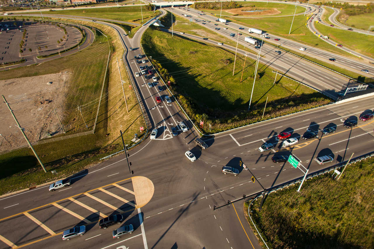 Aerial view of a busy highway intersection with cars and green surroundings.