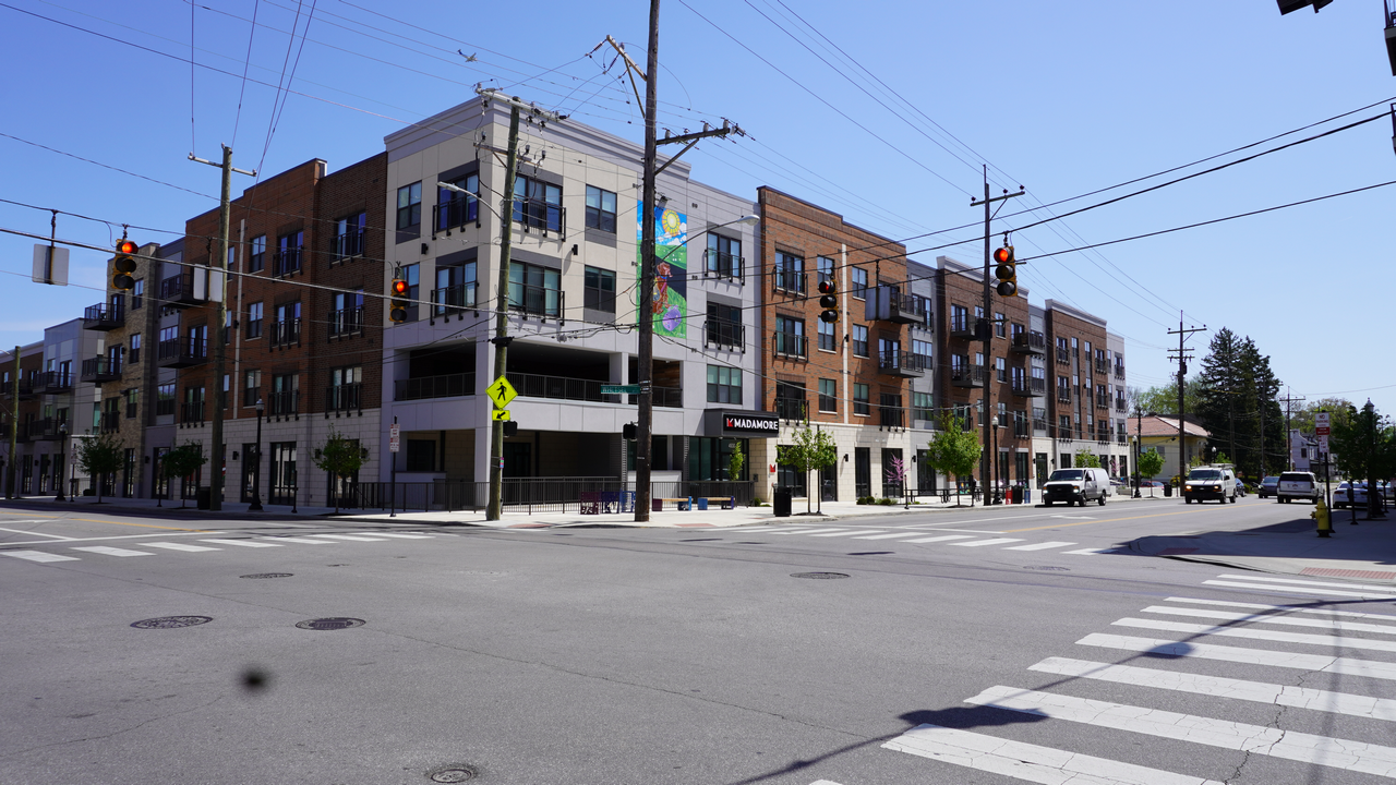 Urban intersection with modern apartment buildings, clear sky, and traffic lights.