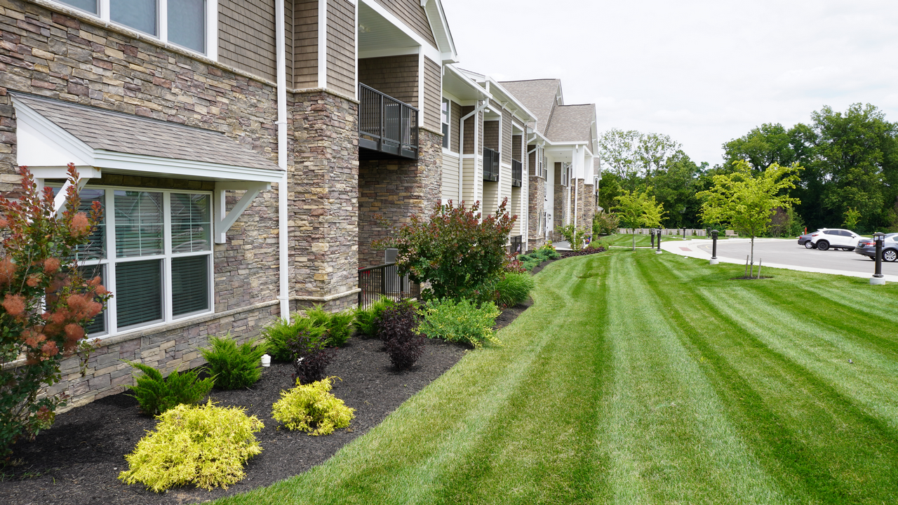 Apartment building with landscaped lawn and shrubs.