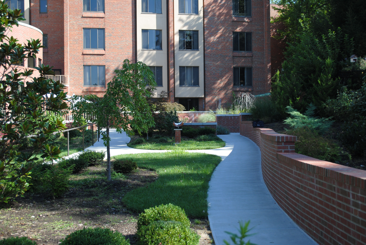 Brick building with a garden path and manicured shrubs.