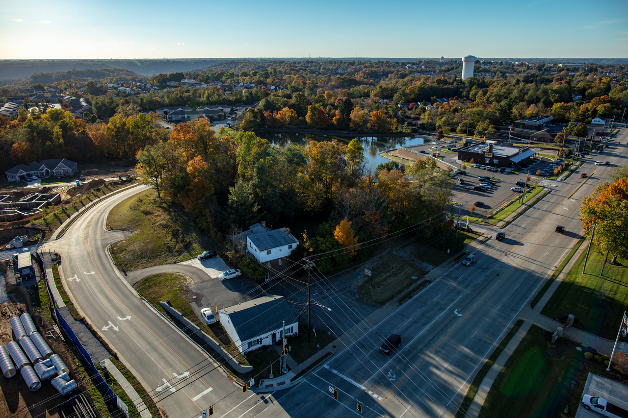 Aerial view of autumn trees, roads, and buildings under a clear sky.