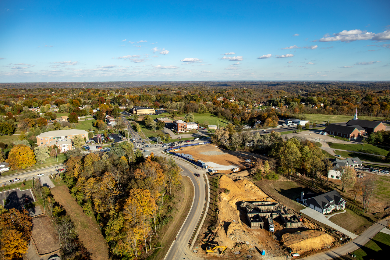 Aerial view of a town with roads, autumn trees, and ongoing construction.