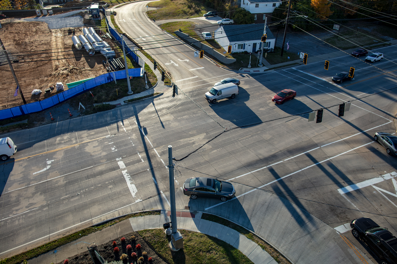 Aerial view of cars at a sunlit intersection with a construction site nearby.
