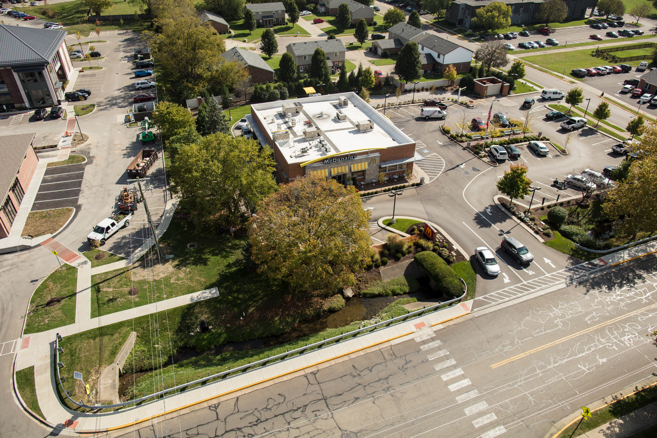Aerial view of a small town intersection with cars, trees, and buildings.
