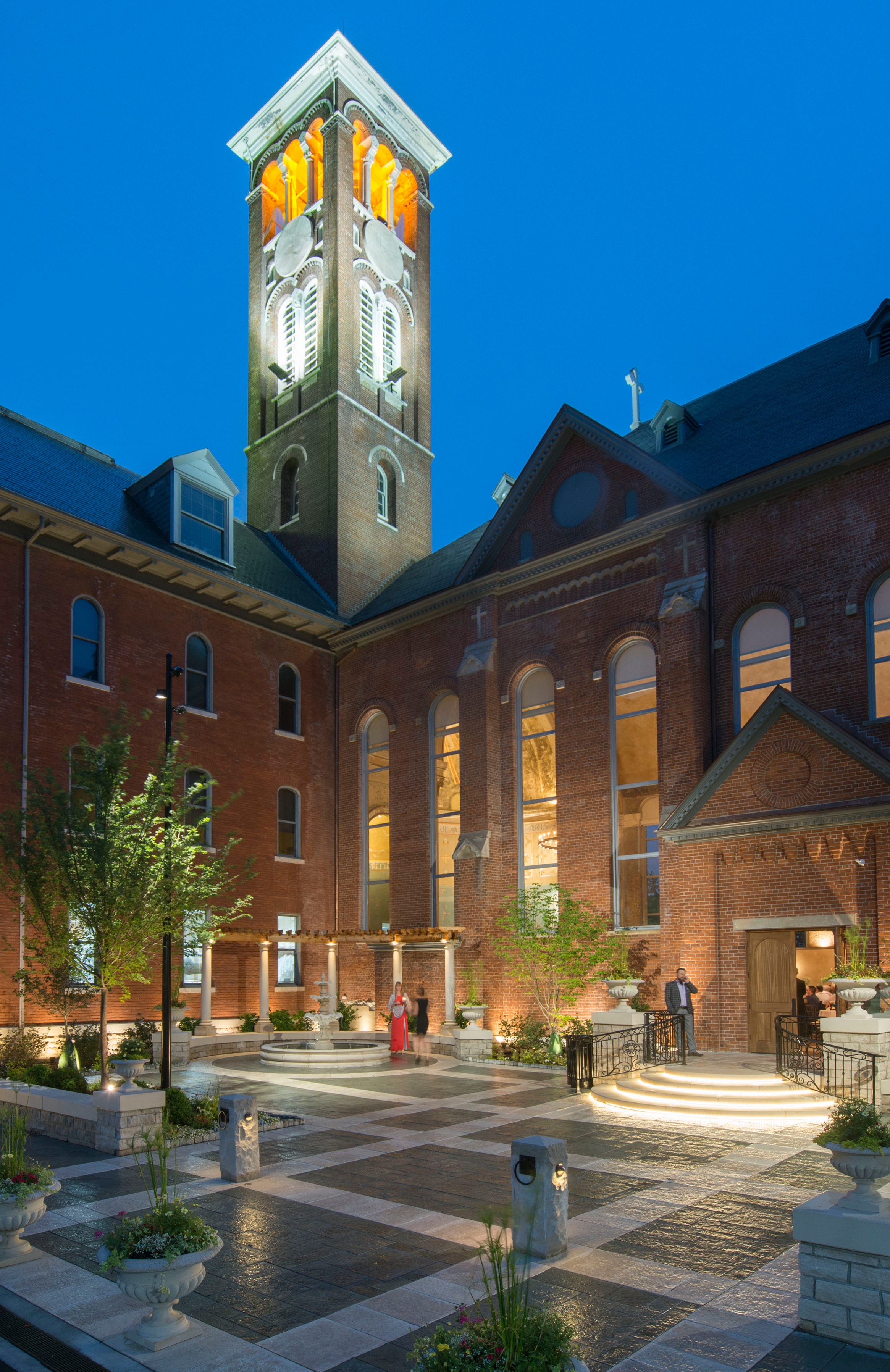 Historic brick building with an illuminated clock tower at dusk.