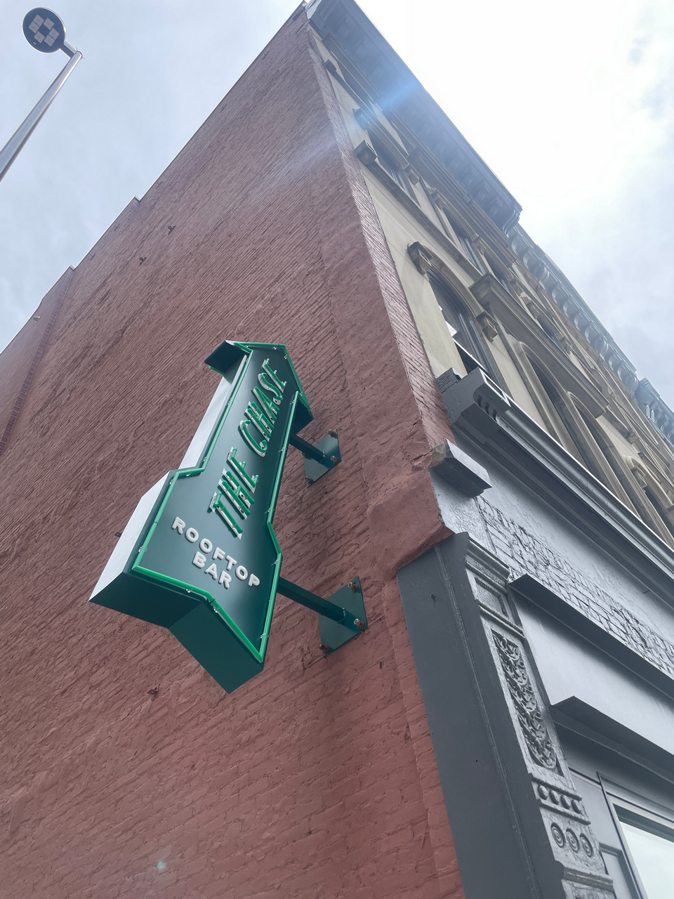 Green sign on a brick building reading 