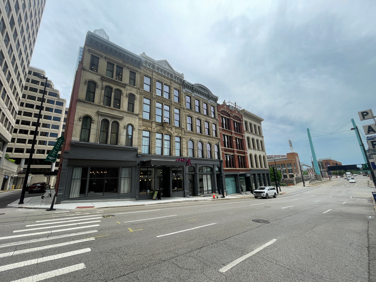 Historic buildings line a quiet city street under a cloudy sky.