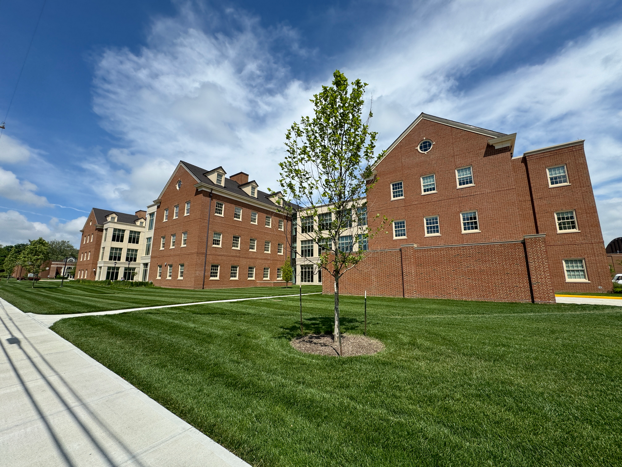 Red brick building with lush green lawn under a cloudy sky.