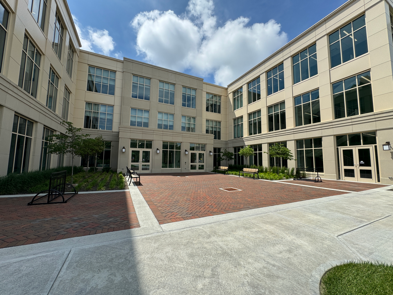 Courtyard of a modern office building, clear sky, and clouds above.