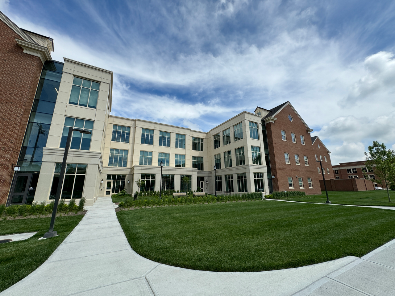 Modern building with glass and brick facade, under a cloudy sky.