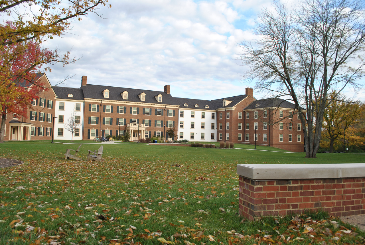 Brick building with white accents, surrounded by trees on a grassy lawn.