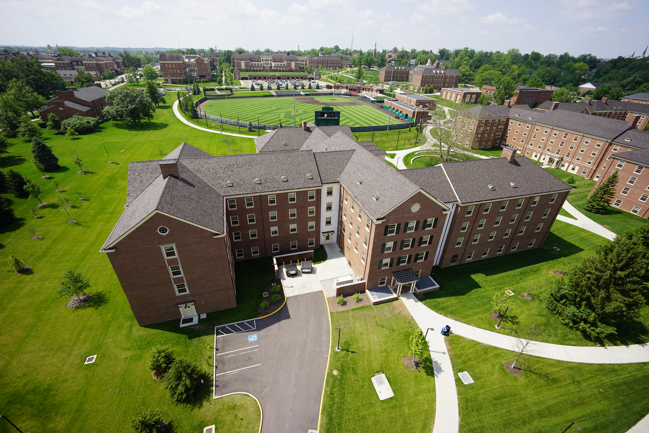 Aerial view of a large red-brick building on a grassy campus with pathways.