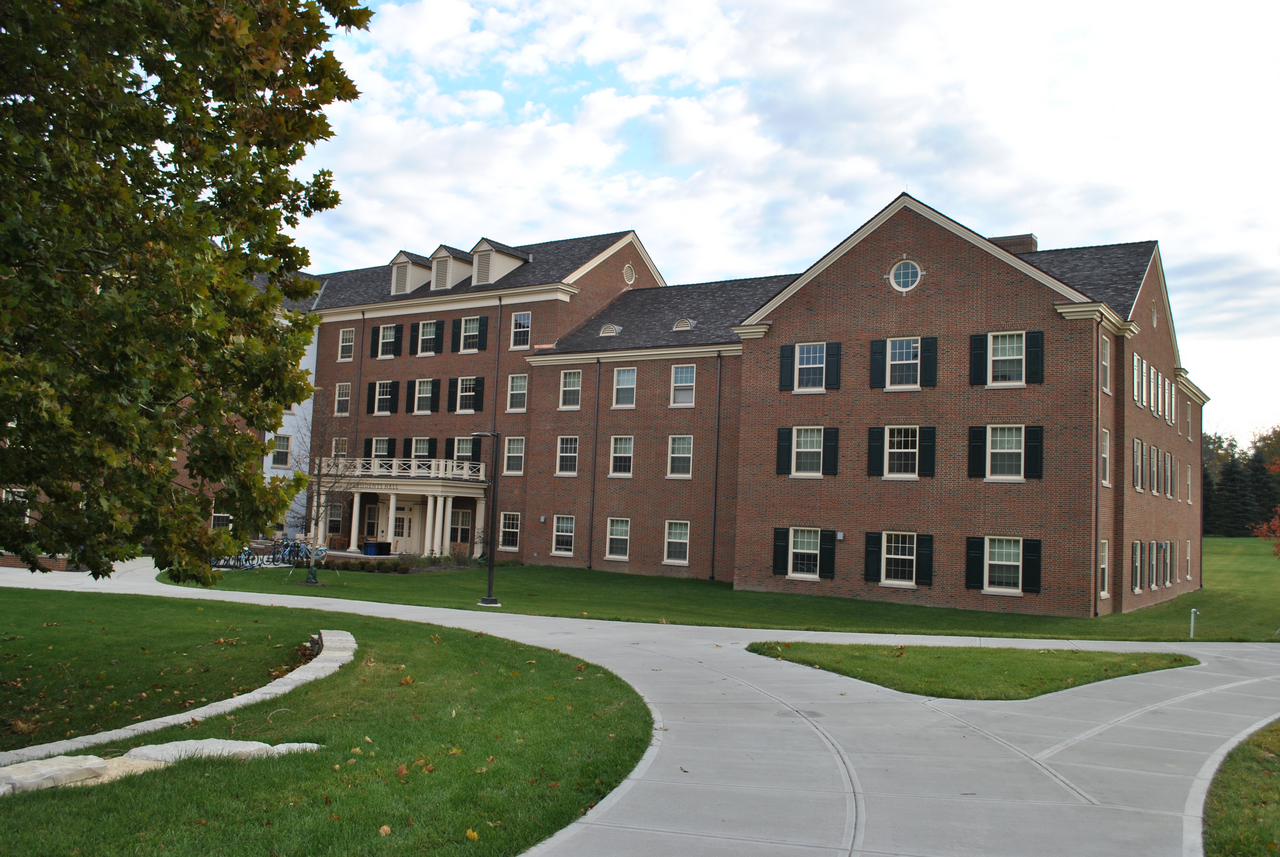 A brick building with dormers, surrounded by grass and pathways.