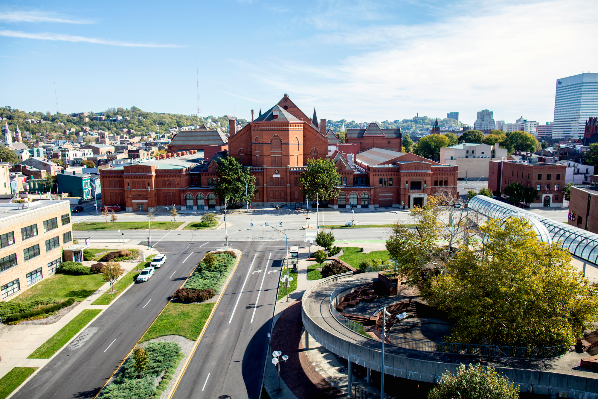 Aerial view of a city street, red brick building, and trees under a blue sky.