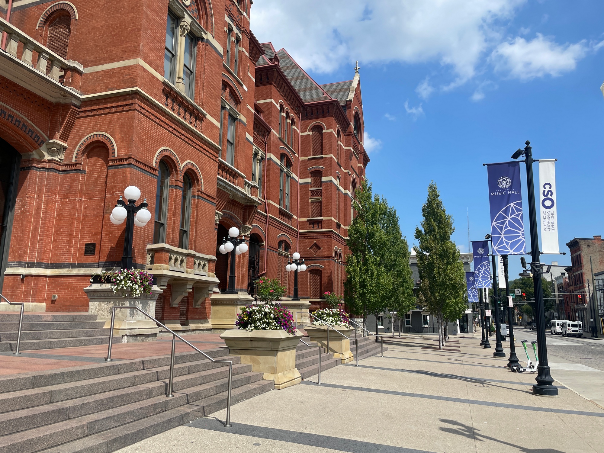 Historic red brick building with ornate details, flanked by street lamps and banners.