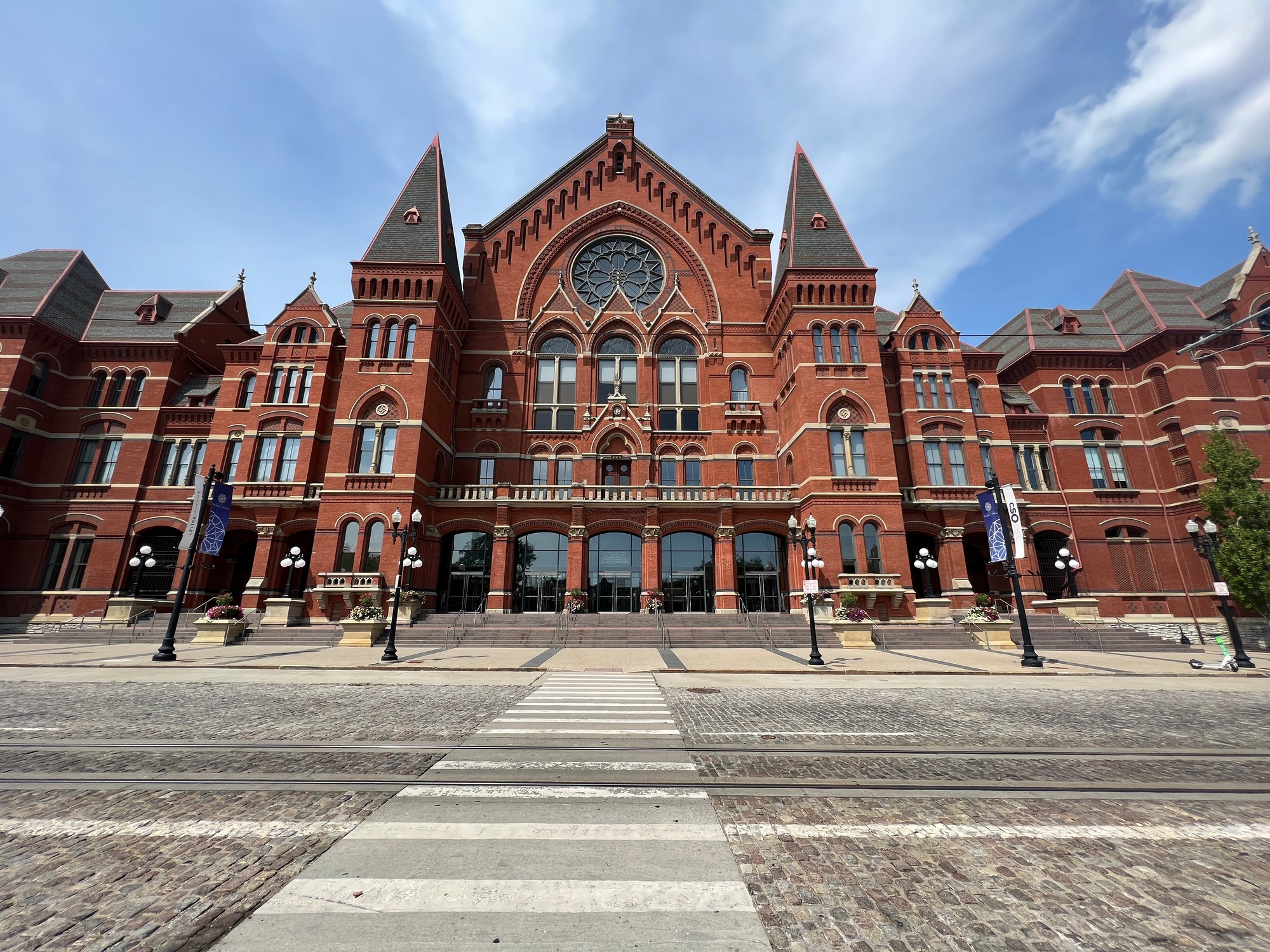 Historic red brick building with large arched windows and spires under a blue sky.