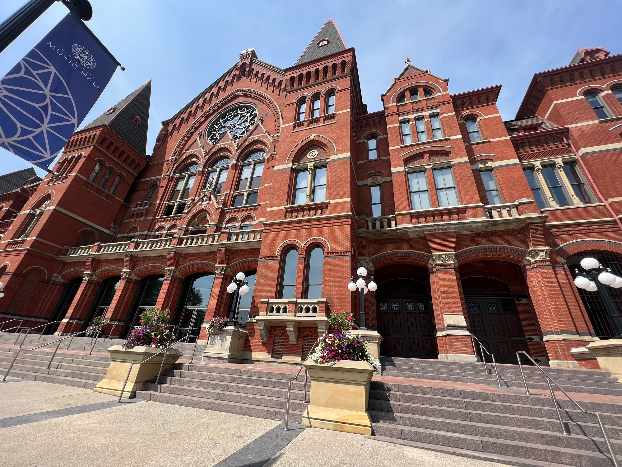 Historic red brick building with ornate windows and banners, under a clear sky.