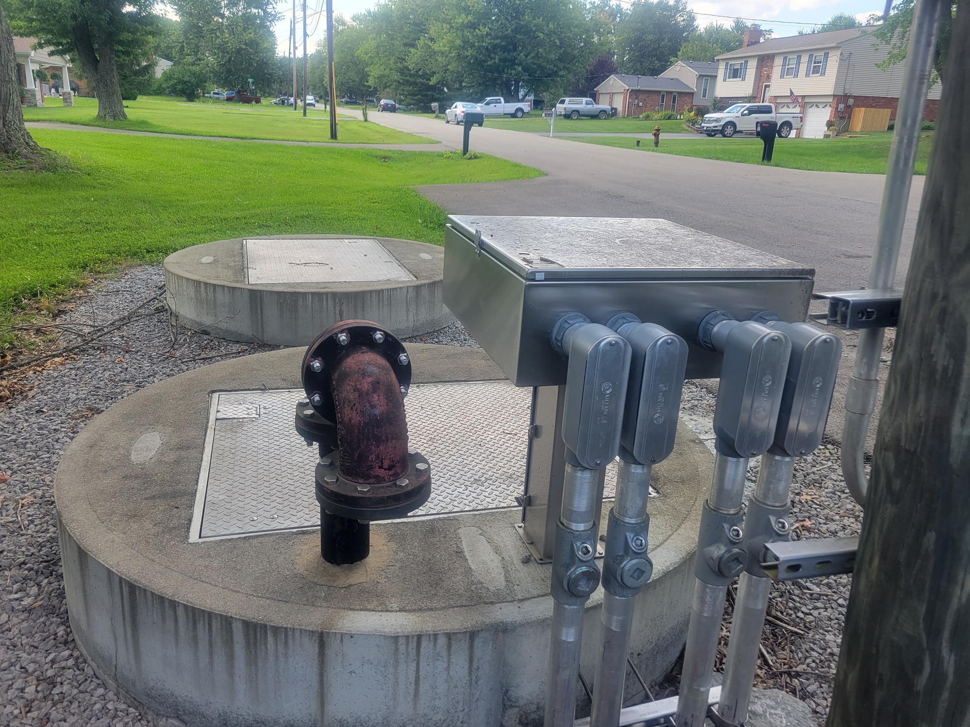 Concrete utility covers and pipes by a residential street.