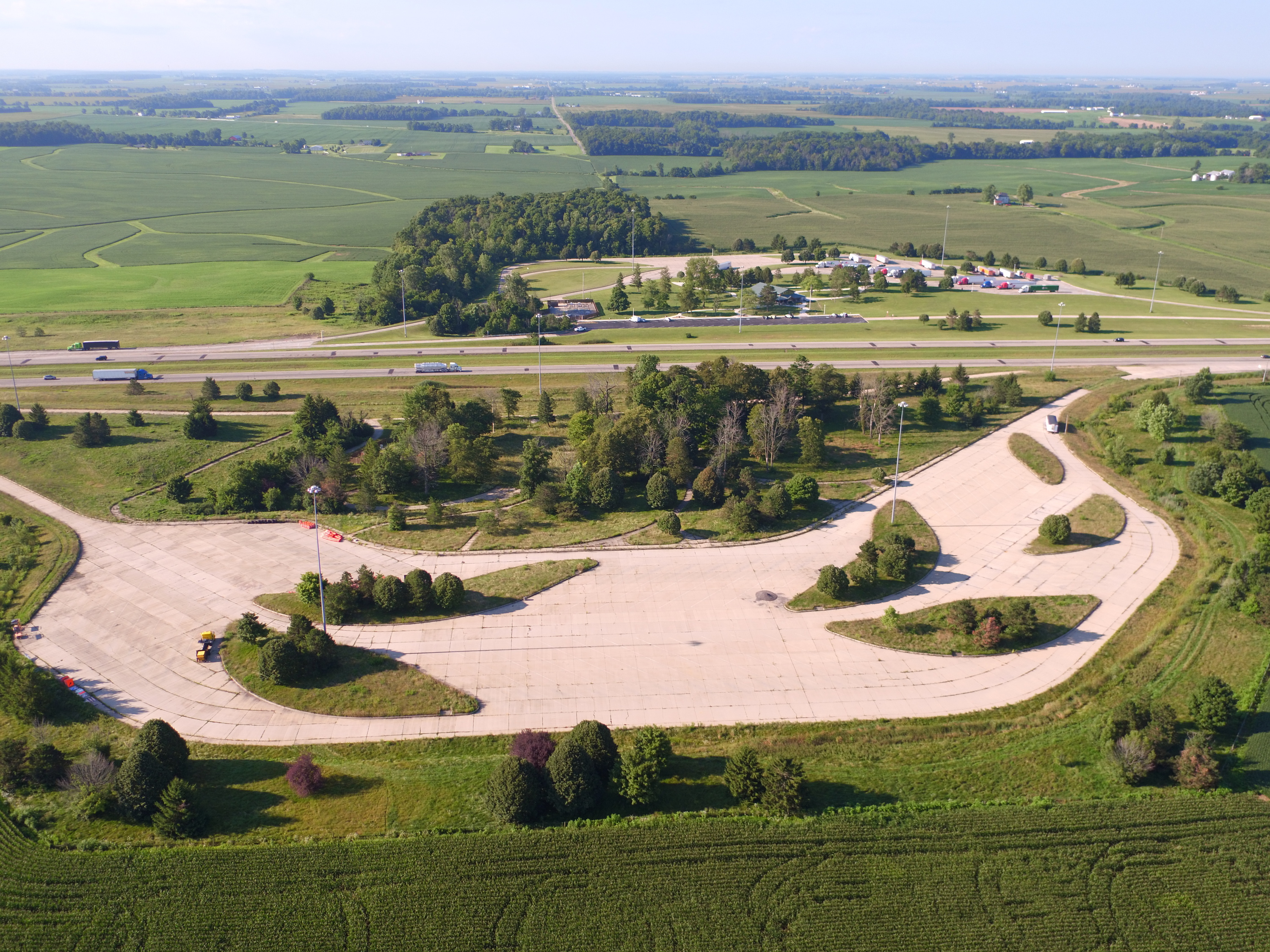 Aerial view of a highway rest area surrounded by fields and trees.