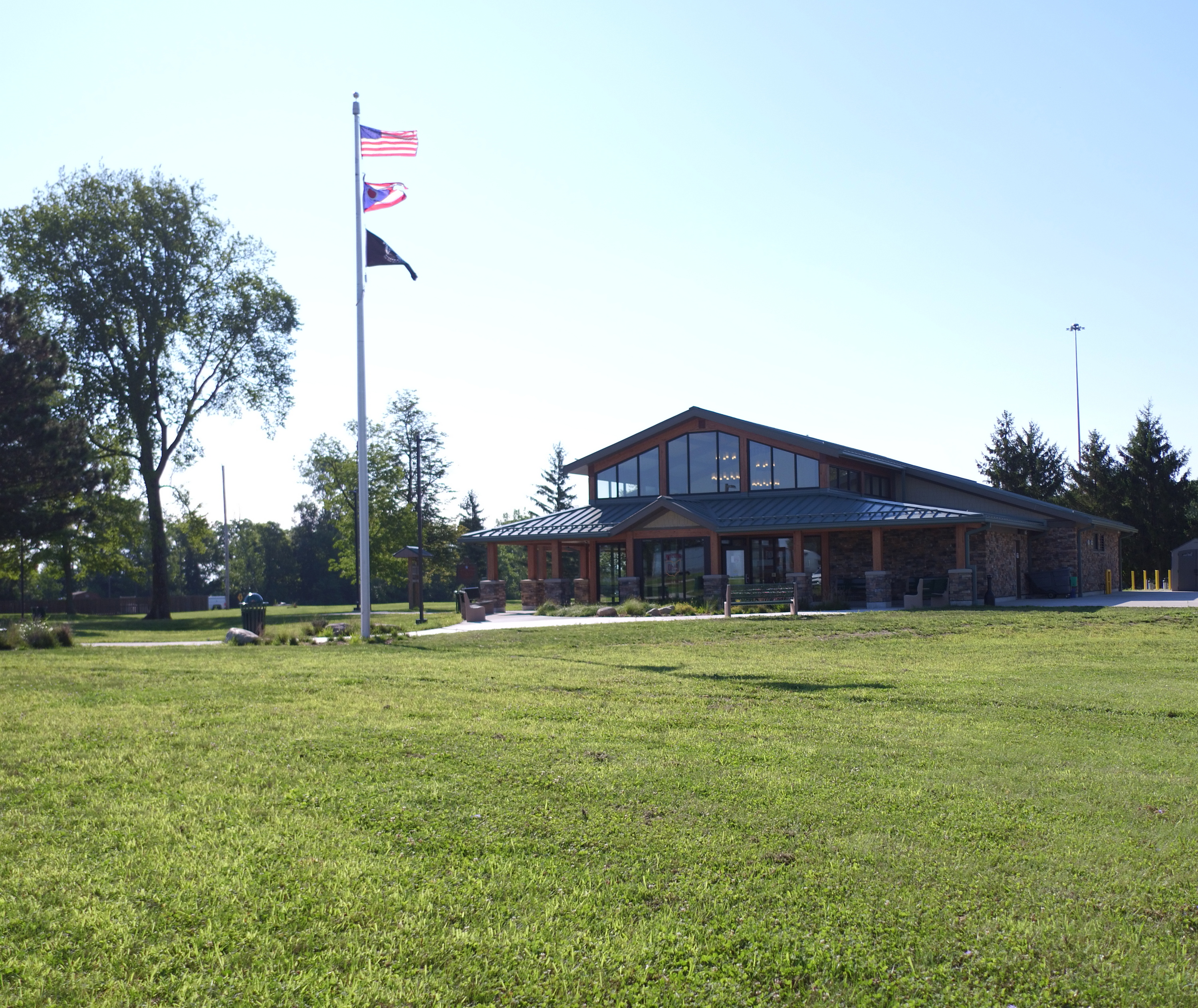 A small building with a triangular roof on a grassy field, flagpole in front.