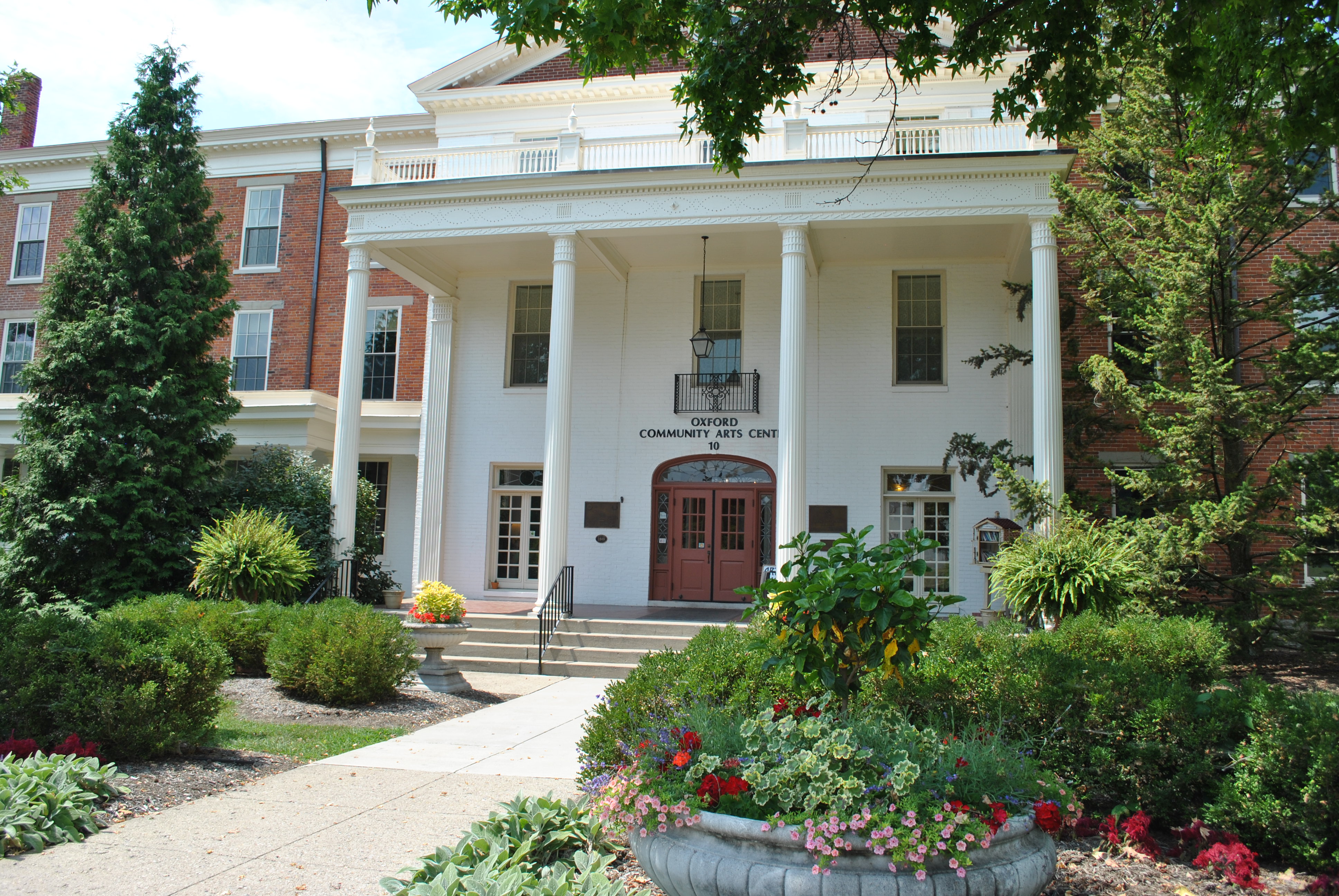 Grand building with columns, lush garden, and red doors.
