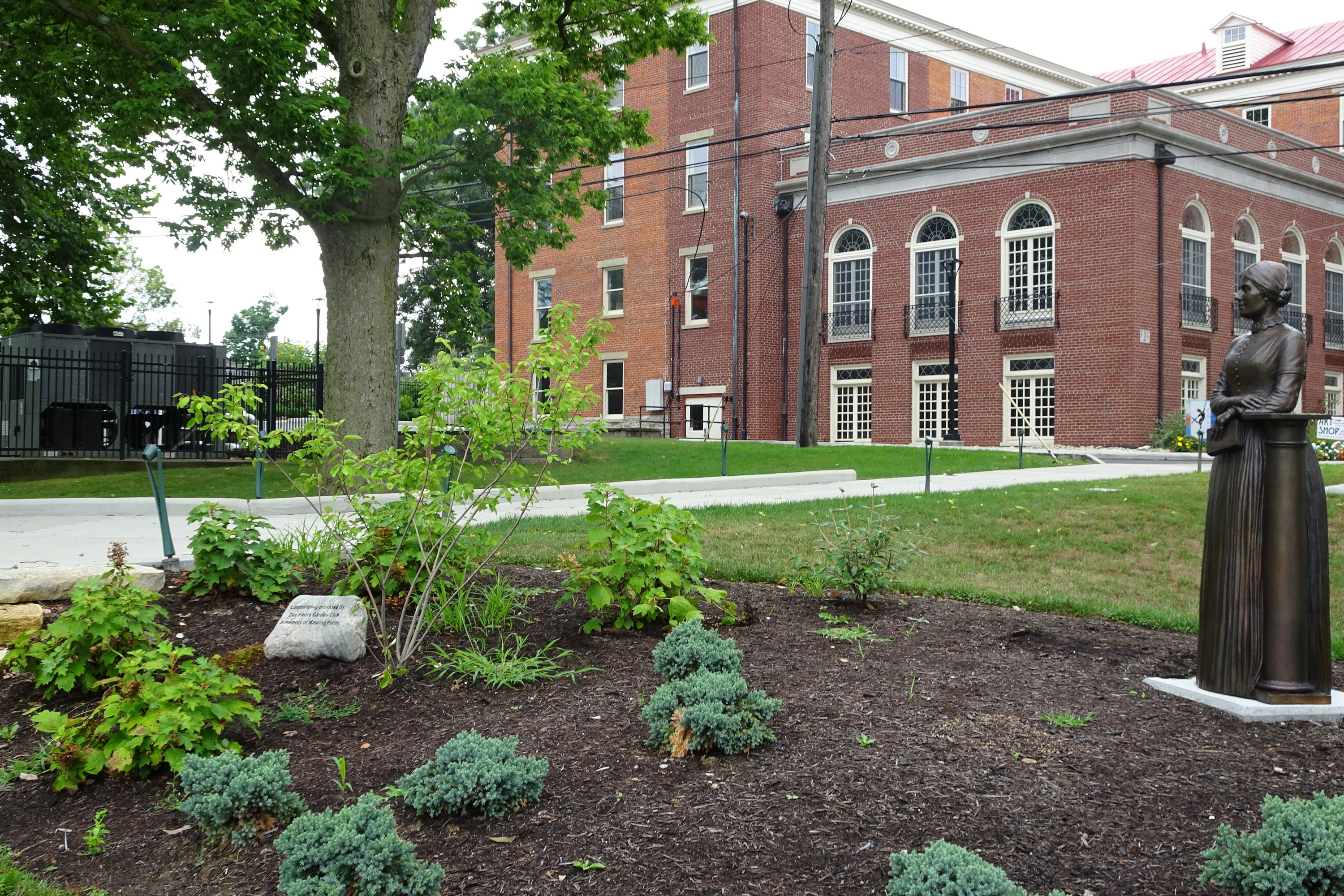Landscaped garden with brick building and statue nearby.