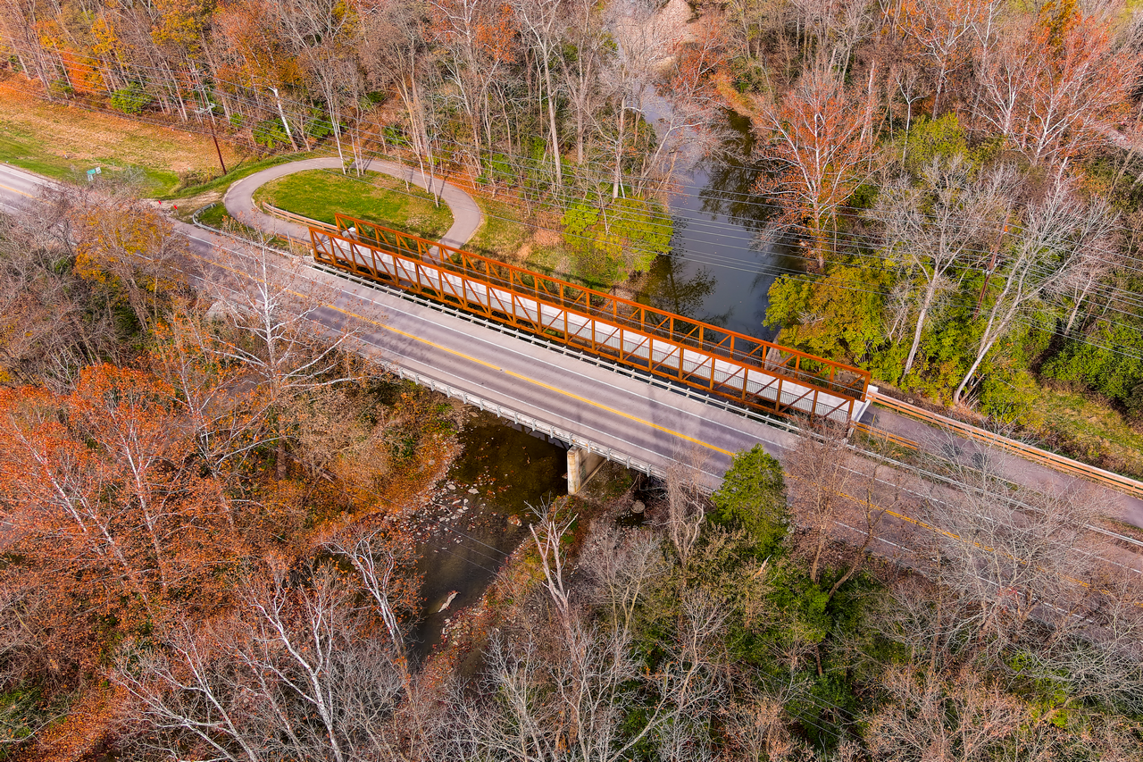 Bridge over a river in an autumn forest, aerial view.