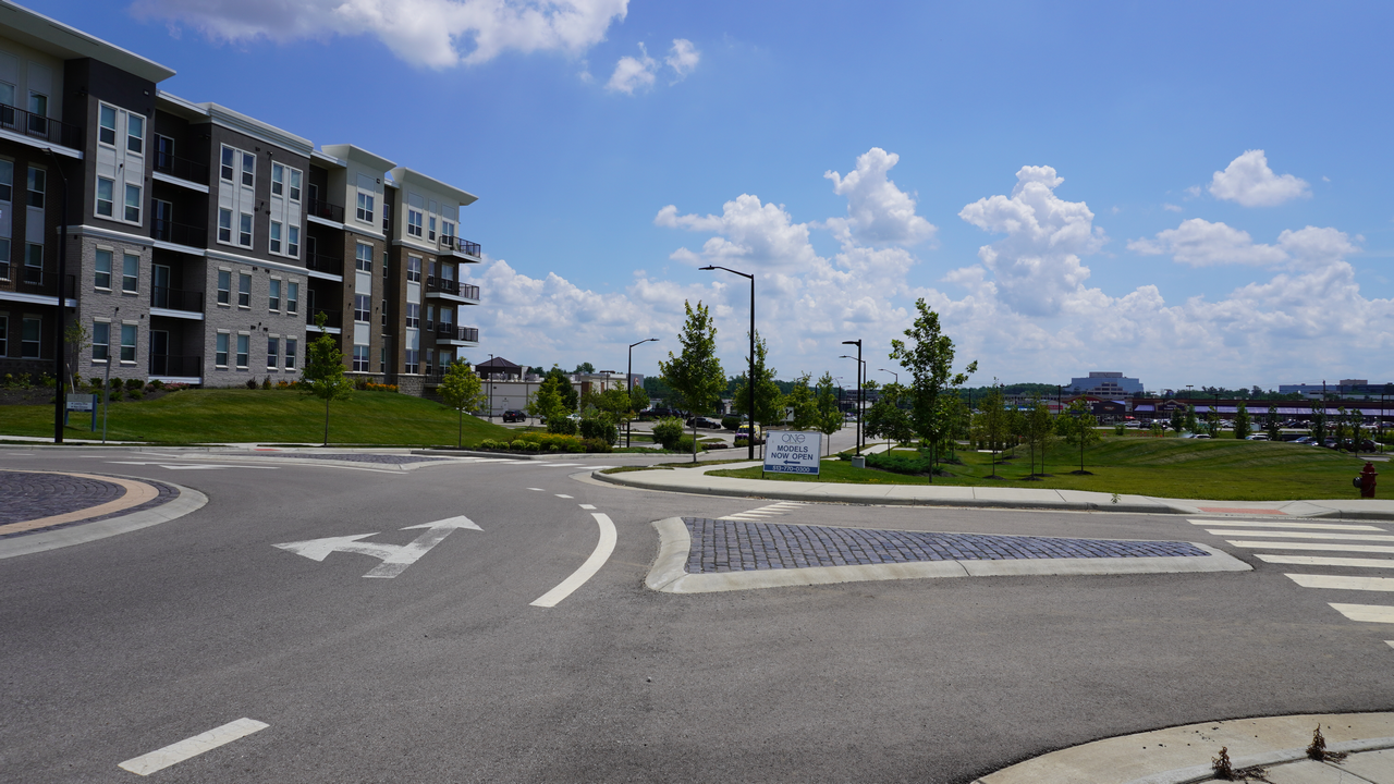 Residential street corner with modern apartments under a blue sky.
