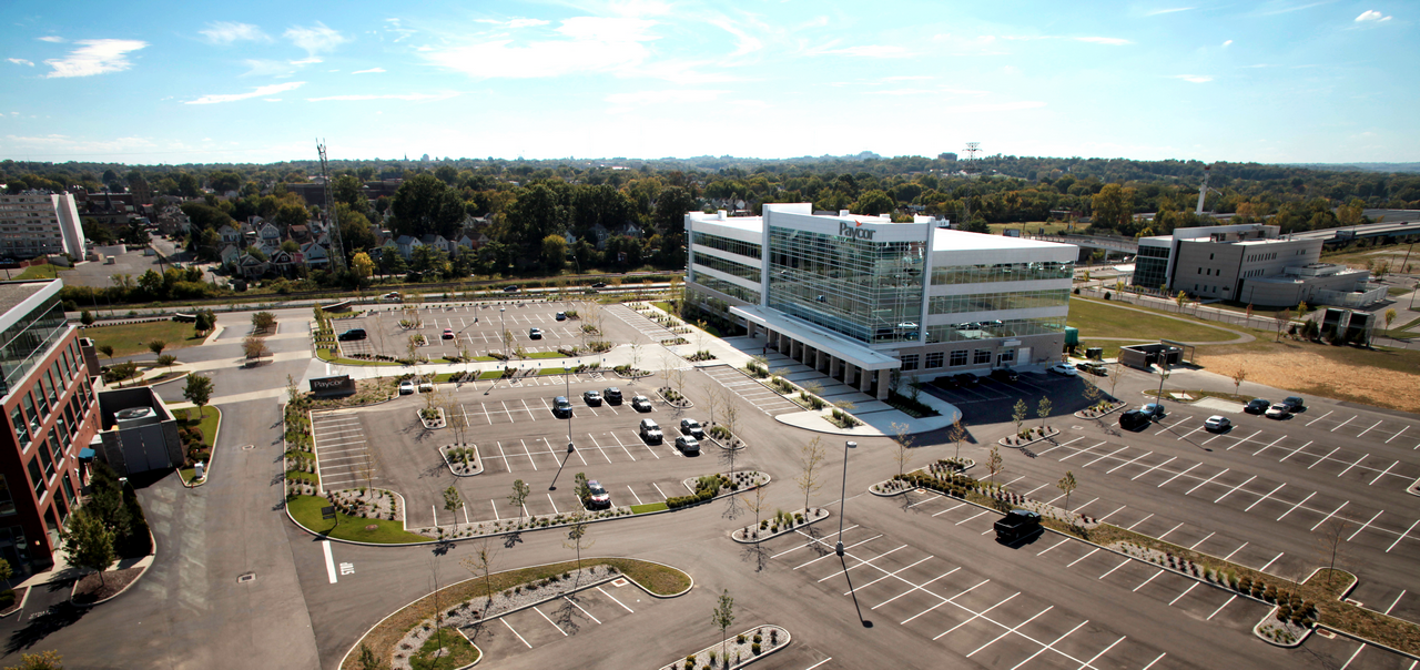Modern office building with large parking lot on a sunny day.