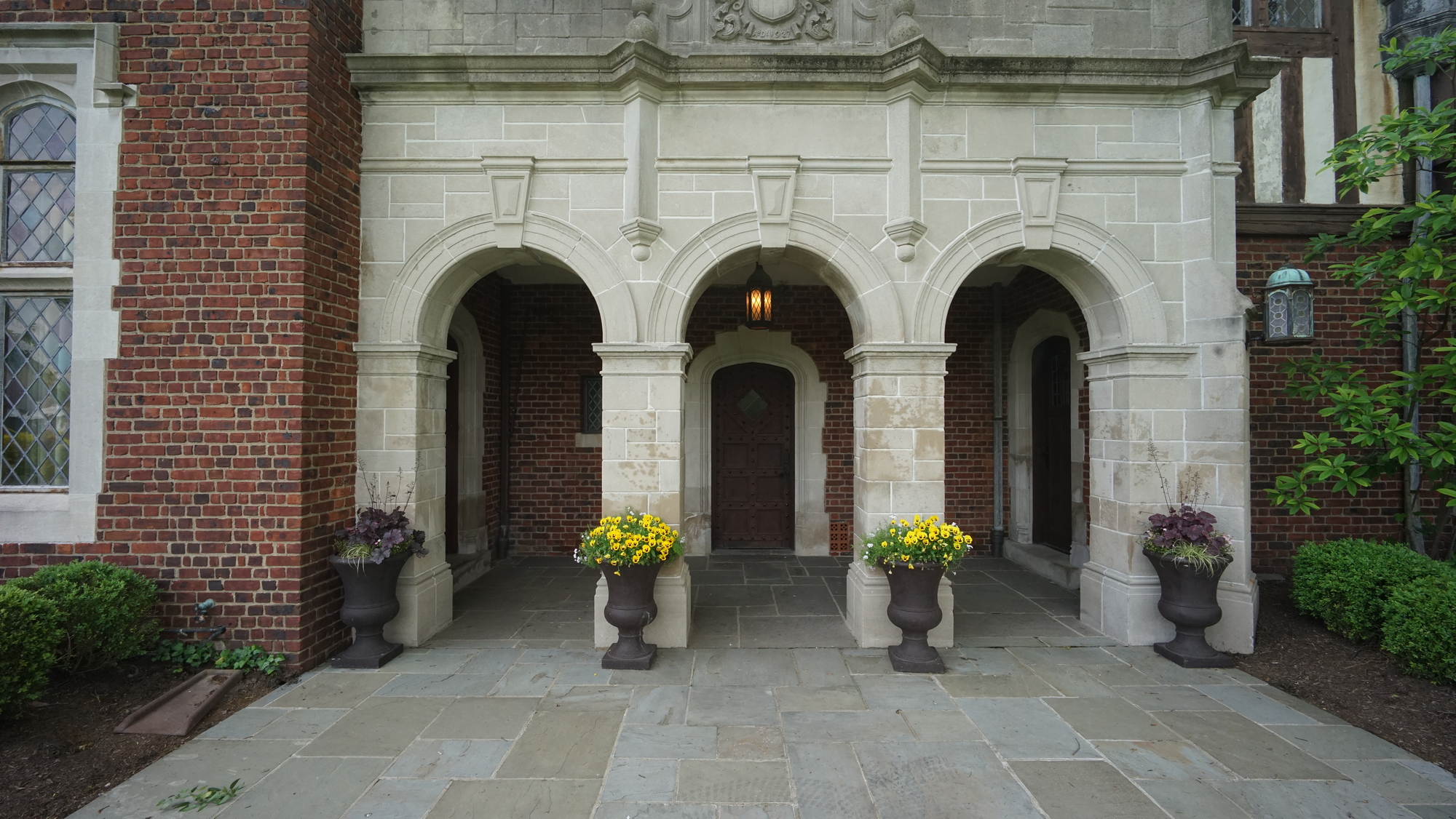 Stone archway entrance with yellow flowers in planters.